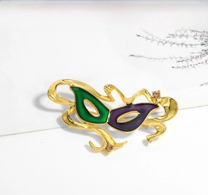 Close-up of Venetian mask brooch with green purple enamel and sparkling rhinestones