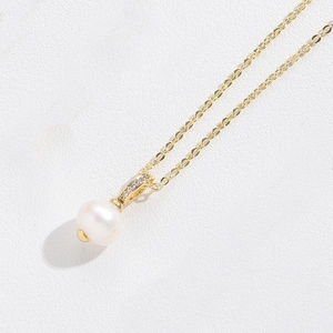 Detail of gold crown pendant necklace with white pearl and sparkling crystals