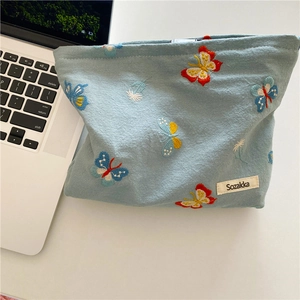 Close-up of sky blue canvas makeup bag with exquisite butterfly and dandelion embroidery