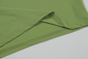 Detail of professional double-needle stitching and overlock edge on green knit fabric