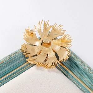 Vintage French floral brooch in gold finish with tassels on a blue retro frame