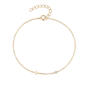 Macro shot of gold cross charm bracelet featuring a single diamond and adjustable chain
