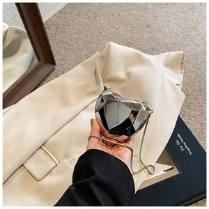 Detailed view of heart-shaped silver metallic clutch bag with elegant chain strap