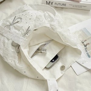 Macro shot of white lace tote bag with silver sequins and interior zipper pocket