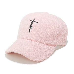 Dettaglio del cappello in lana di agnello rosa con ricamo a croce Faith e consistenza morbida.