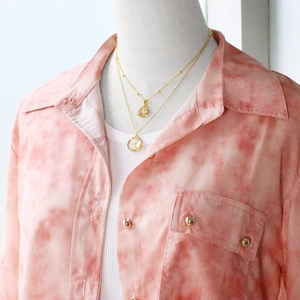 Detail showing layered gold-plated necklaces with sun, moon pendants and shell texture