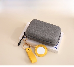 Detailed view of gray fabric storage case and yellow leather AirTag keychain holder