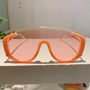 Detail of oversized orange sunglasses with pink gradient lenses and metal nose bridge