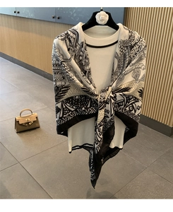 Detailed close-up of a printed silk scarf styled with a black and white knit cardigan