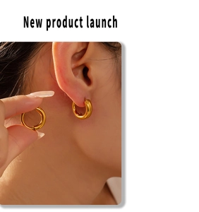Close-up of elegant gold-plated geometric hoop earrings shown on a model's ear
