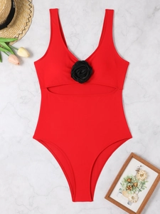 Close-up of red one-piece swimsuit with black 3D flower detail and cutout design