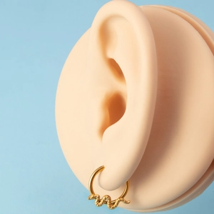 Detailed view of a golden snake-shaped cartilage hoop earring worn on an ear model