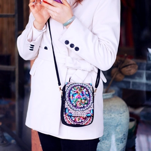 Ethnic crossbody phone bag with colorful floral embroidery and sequins on model