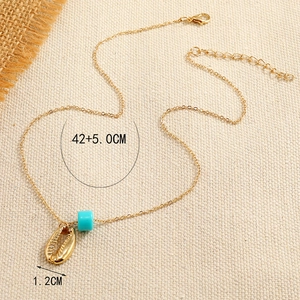 Bohemian gold chain necklace with metallic shell pendant and blue bead on burlap
