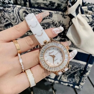 Detailed view of white ceramic watch with gold bezel and mother of pearl dial on wrist