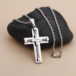 Polished stainless steel cross pendant on a twist rope chain displayed on a natural river stone