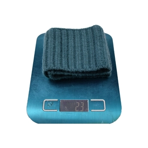 Deep green knitted sports headband on a digital scale showing its lightweight 23g mass