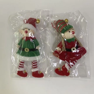 Detail of red and green plush Christmas elf ornaments with gold bells in packaging