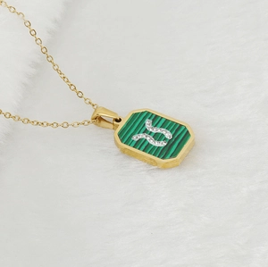 Macro detail of gold stainless steel necklace with green malachite pendant and crystals