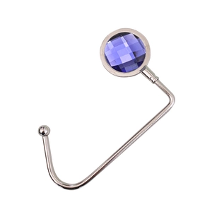 Detail of silver portable table hook featuring a faceted purple crystal stone inlay