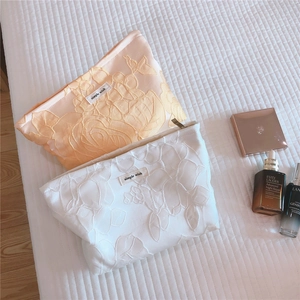 Close-up of elegant floral embossed texture and silk-like fabric on zip makeup bag