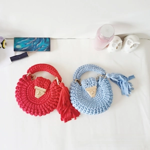 Detail of red and blue crochet round bags with cotton tassels and metal buckles