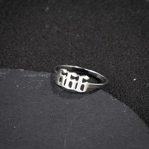 Macro shot of stainless steel angel number 666 ring on dark stone texture