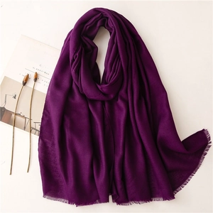 Detalle de bufanda morado oscuro efecto lino con flecos finos y fondo minimalista