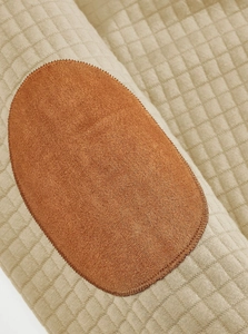 Close-up of khaki quilted square pattern fabric with brown oval elbow patch detail