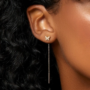 Close-up of gold butterfly tassel earring with white zircon inlay on model ear