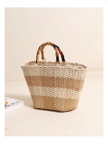Detailed view of handmade woven straw bag with natural bamboo handles and metal rings