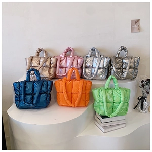 Detailed row of quilted metallic puffer tote bags in vibrant colors on a minimalist stand