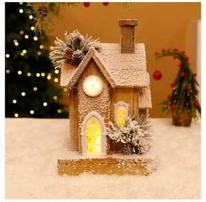 Close-up of lighted wooden Christmas house with artificial snow and pine cone details