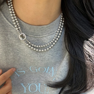Detail of silver double-layered beaded necklace featuring a square pavé zircon pendant