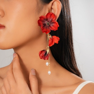 Detailansicht der roten Stoffblumen-Ohrringe mit Goldketten und weißen Perlen am Model