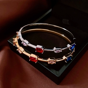 Detail of 18K gold plated square clasp bracelets with colorful gemstones on silk fabric
