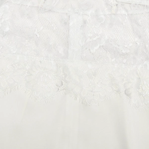 Détail de la broderie en dentelle florale et texture du tissu blanc soyeux