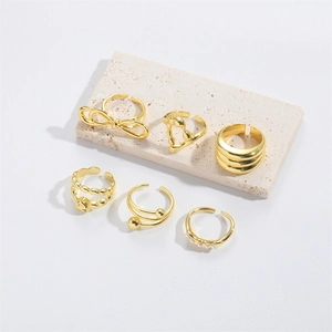 Detail view of 6 gold adjustable rings featuring bow, heart and pearl designs