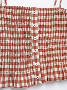 Close-up of smocked red and white gingham fabric with white buttons on the crop top