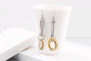 Détail de boucles d'oreilles anneaux bicolores or et argent sur une tasse en porcelaine