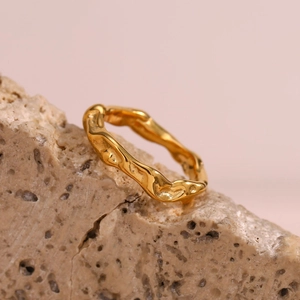 Detailed view of the gold-plated irregular wavy texture ring on a natural stone base