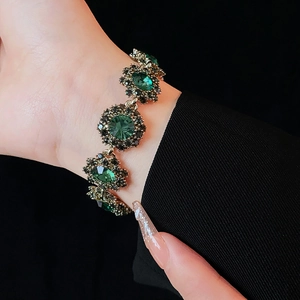 Detailed shot of vintage gold bracelet with large green gemstones on model wrist