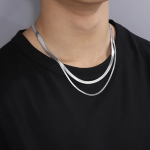 Close-up of double layer silver snake chain necklace worn on a black round neck shirt