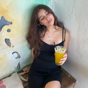 Close-up of the black V-neck lace strap dress on model against a vintage wall