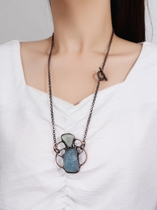 Close-up of vintage aquamarine and fluorite pendant on model with bronze metal chain