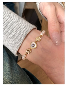 Détail d'un bracelet en perles plaqué or avec des breloques fleurs en zircon bleu