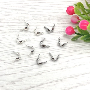 Close-up of silver stainless steel jewelry crimp bead connectors on white wood surface