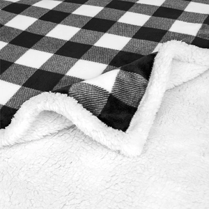 Detail of black and white plaid flannel blanket with white thick sherpa lining stitching