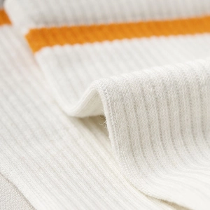 Macro detail of soft ribbed knit texture on cream socks with vibrant orange stripe