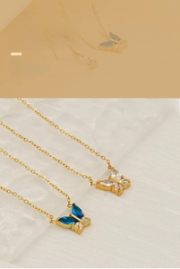 Detailed close-up of butterfly pendants featuring blue and clear zircon crystals